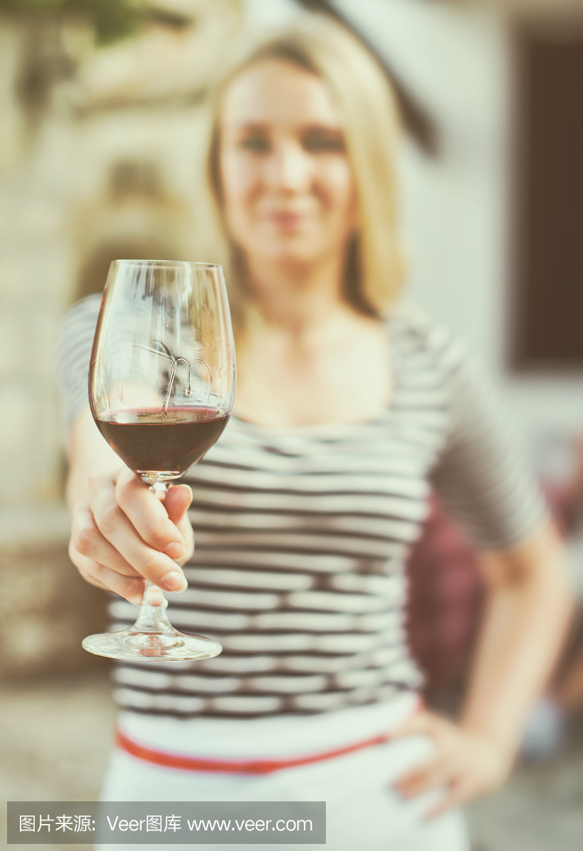 一個女人在室外遞上一杯紅酒。復(fù)古的效果。